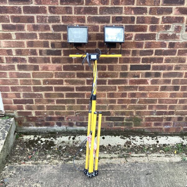 Yellow halogen site light with tripod base for outdoor work.