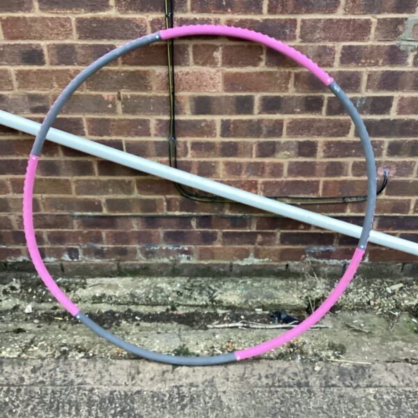 Large pink and grey exercise hoop for fitness workouts.