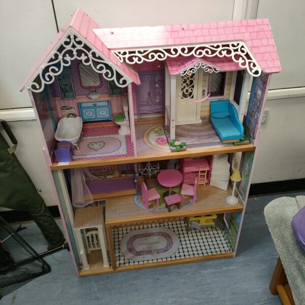 Large pink dolls house with furnished rooms, a colourful toy.