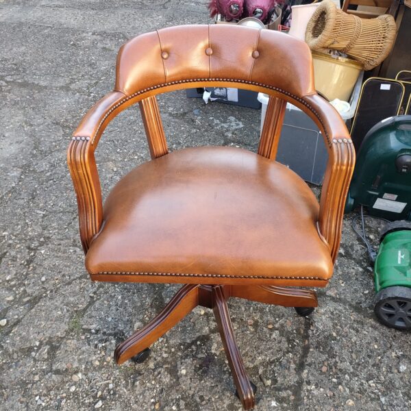 Brown leather captains chair with swivel base.