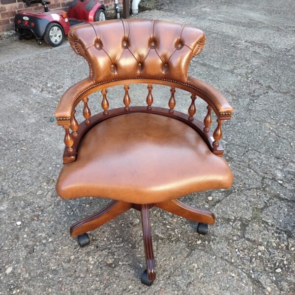 Vintage leather captains chair with swivel base and dark wood frame.
