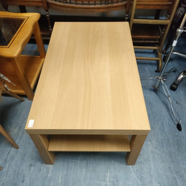 Light wood coffee table with lower shelf, side view.