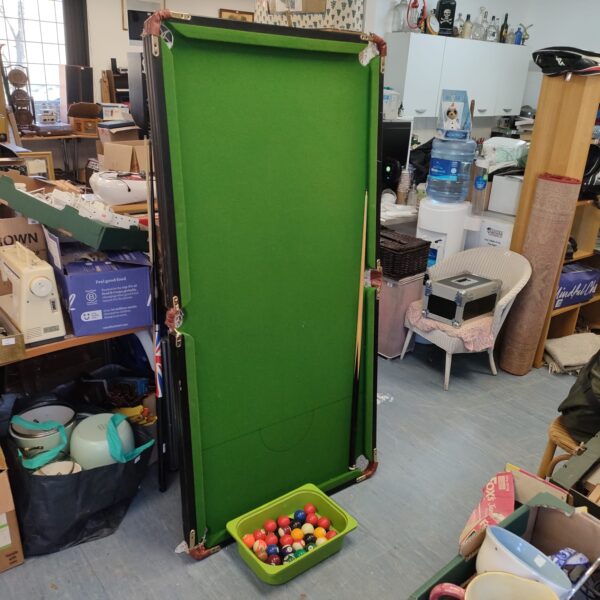 Green folding snooker table with accessories for home games.
