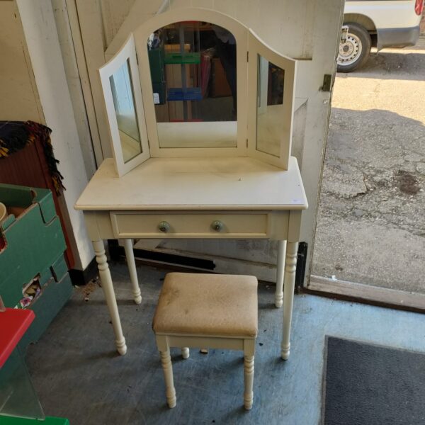 White dressing table with mirror and stool in a bedroom setting.