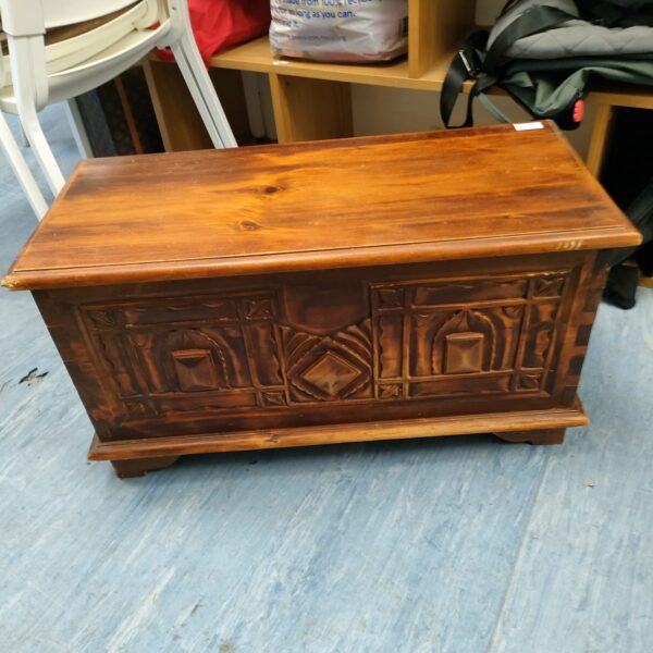 Vintage carved wooden blanket box with decorative front panel.