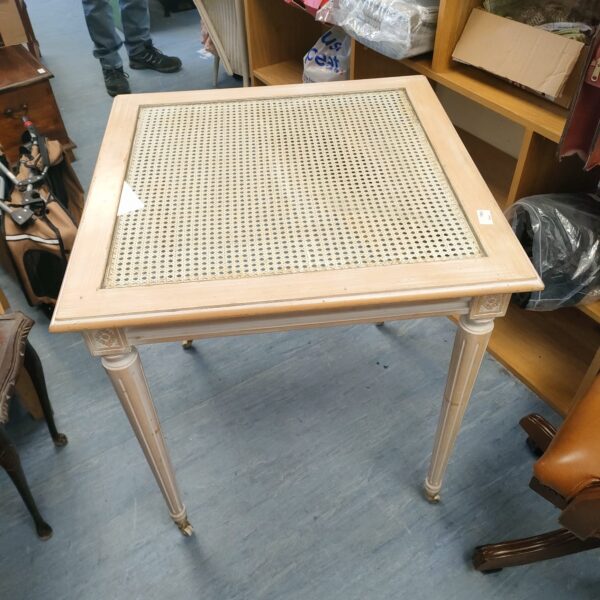 White washed rattan glass top table with casters.