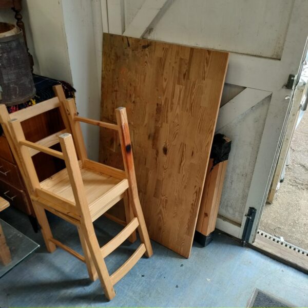 Rustic pine table and two chairs in a farmhouse setting.