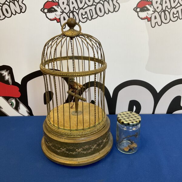 Antique Victorian bird automaton in ornate brass cage, a collectible curiosity.