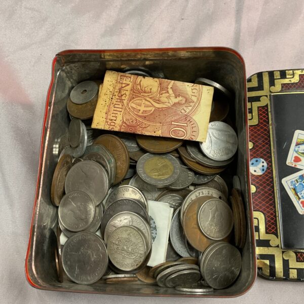 Vintage tin filled with assorted foreign and collectible coins.