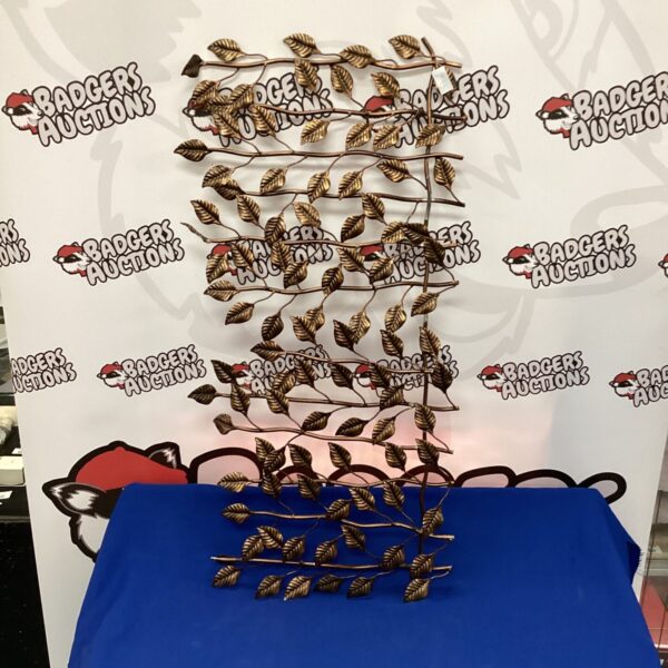 Abstract bronze effect wall art with flowing leaf-like design.