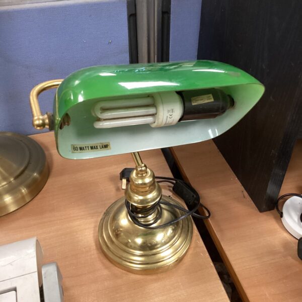 Vintage green bankers lamp with brass base on a dark surface.