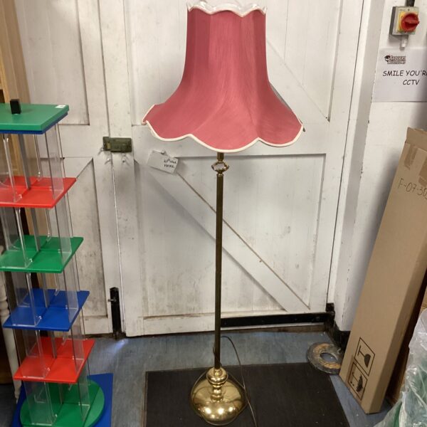 Vintage brass standard lamp with a pink shade, classic floor lighting.
