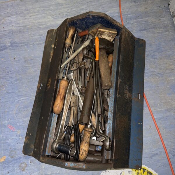 Vintage metal toolbox filled with a variety of hand tools.