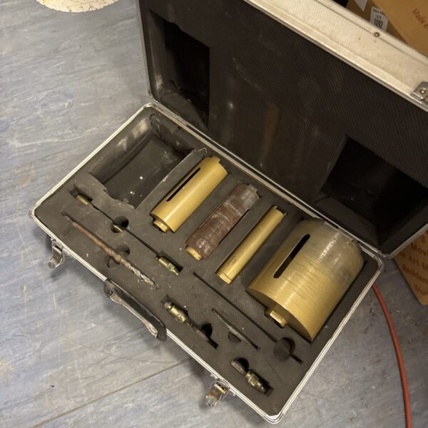 Borehole drill bit set in a worn carrying case.