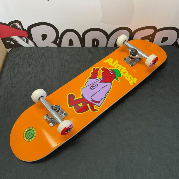 Vibrant orange Almost skateboard with peace sign graphic and Tensor trucks.