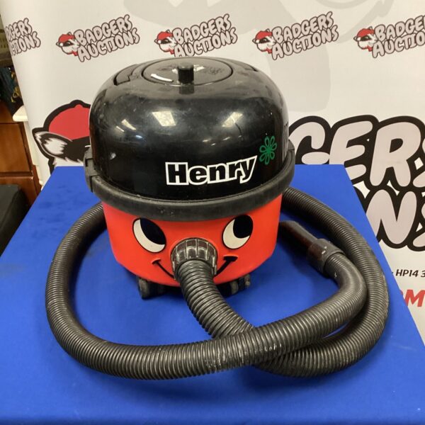Red Numatic Henry vacuum cleaner with hose visible.