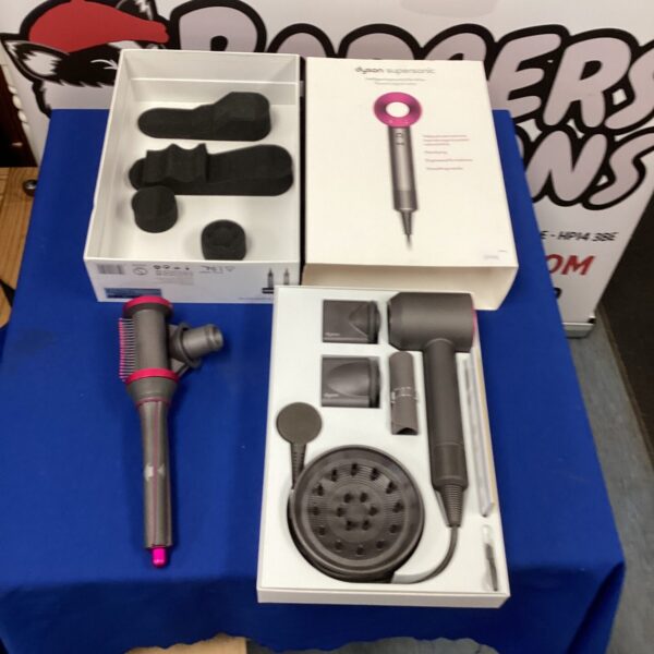 Dyson Supersonic HD03 hair dryer with attachments displayed on a table.