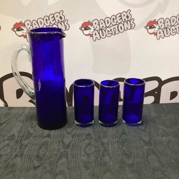 Vibrant cobalt blue art glass pitcher and tumblers set on display.