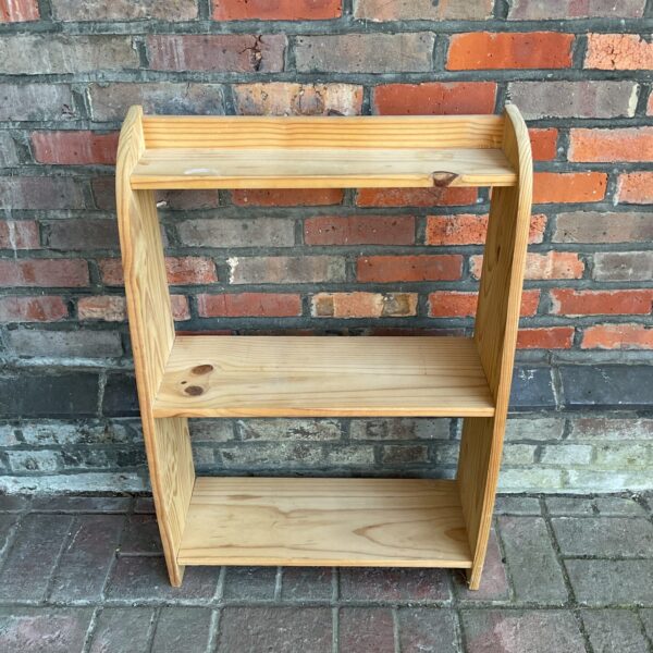 Small pine bookcase with three tiers for home storage.