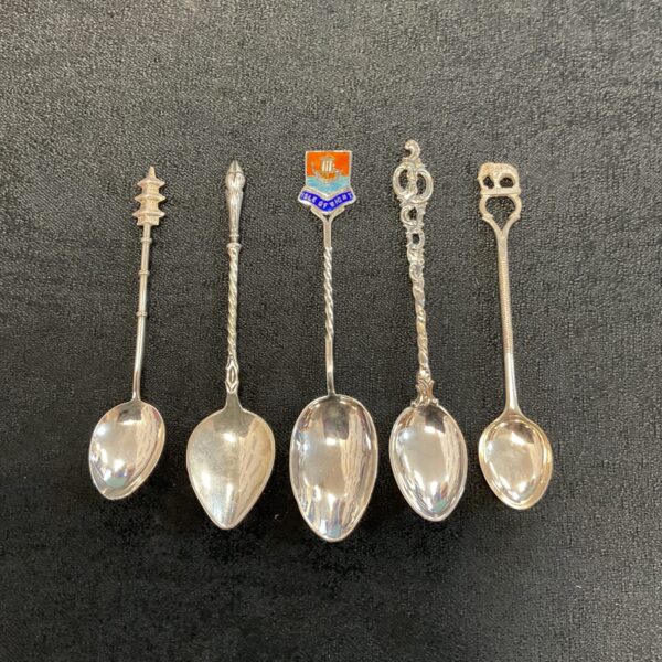 Lot of five silver collector spoons with varied designs.
