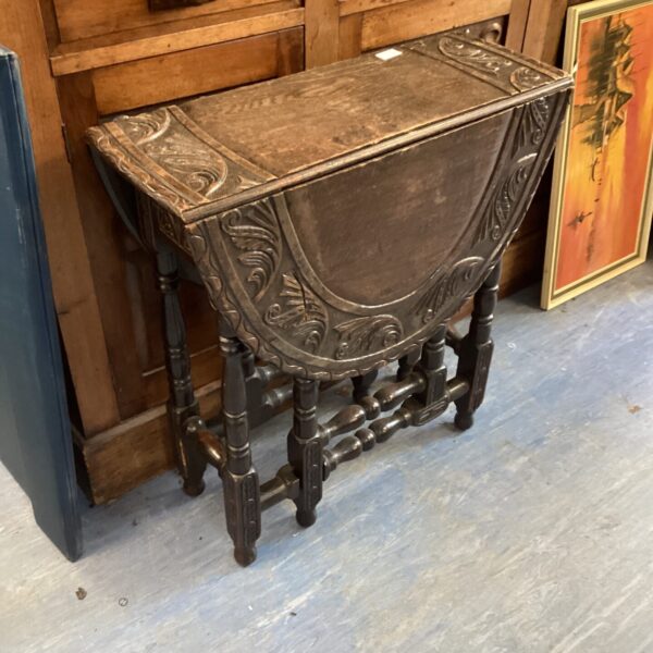 Vintage carved drop leaf table in dark wood.