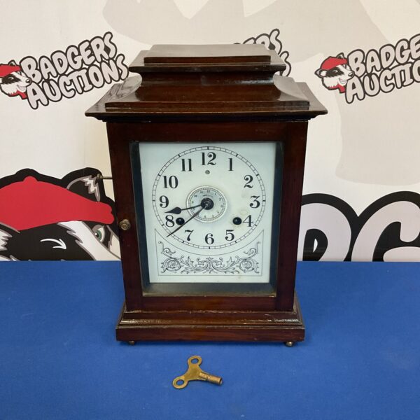 Antique John Bull alarm mantle clock with key, front view.