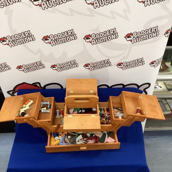 Vintage wooden cantilever sewing box filled with sewing supplies.