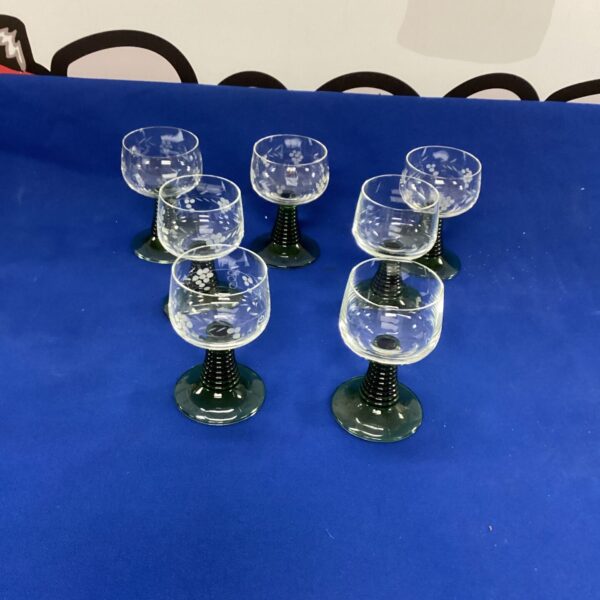 Set of seven vintage French green wine goblets on display.