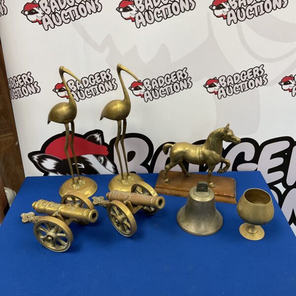 Vintage brass canon and bell lot on display.