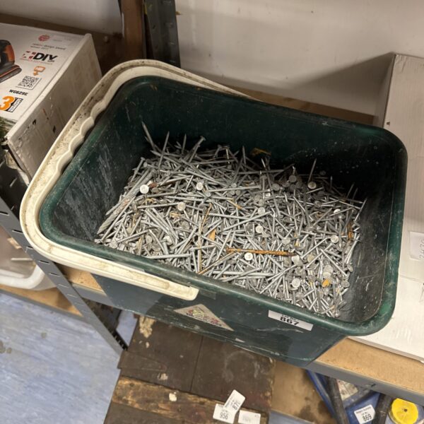 Assorted metal nails in a plastic bucket for DIY projects.