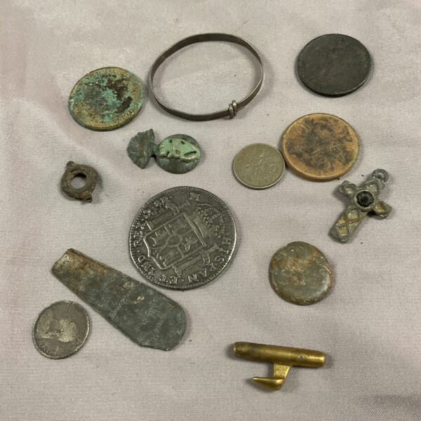 Collection of metal detecting finds including coins and a buckle.
