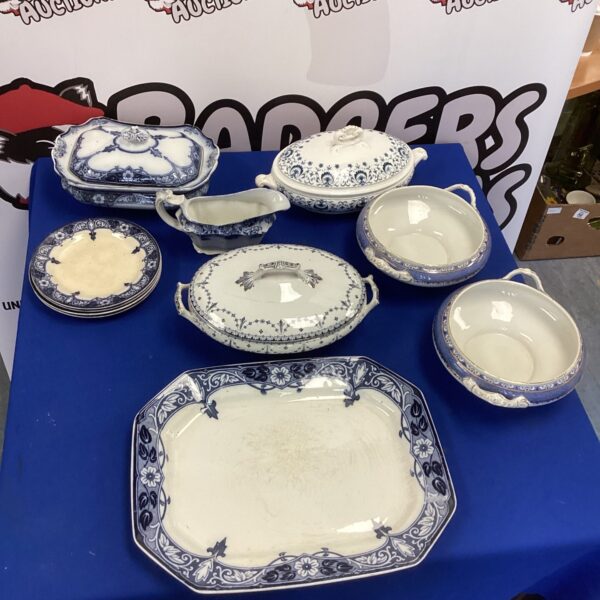 Vintage china terrines and plates displayed on a blue surface.