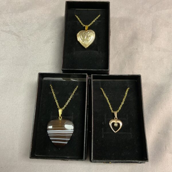 Lot of three silver gilt heart pendant necklaces with floral details.