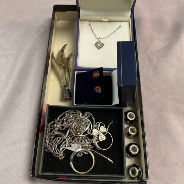 Vintage silver jewellery tray with rings and necklaces displayed.