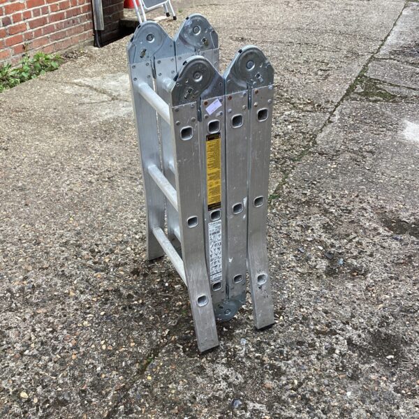 Silver aluminium multi purpose ladder leaning against a wall.