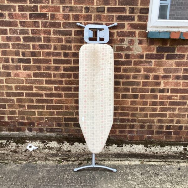 Vintage metal ironing board with a flat surface and folding design.