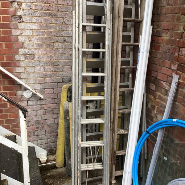 Used aluminium triple ladder leaning against a brick wall.