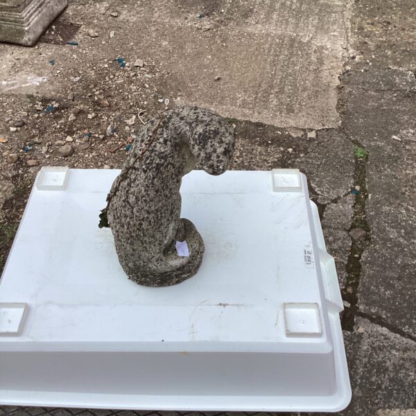 Vintage concrete otter garden ornament in an outdoor setting.