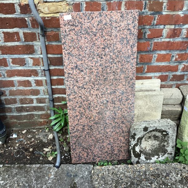 Red granite worktop slab with speckled pattern.