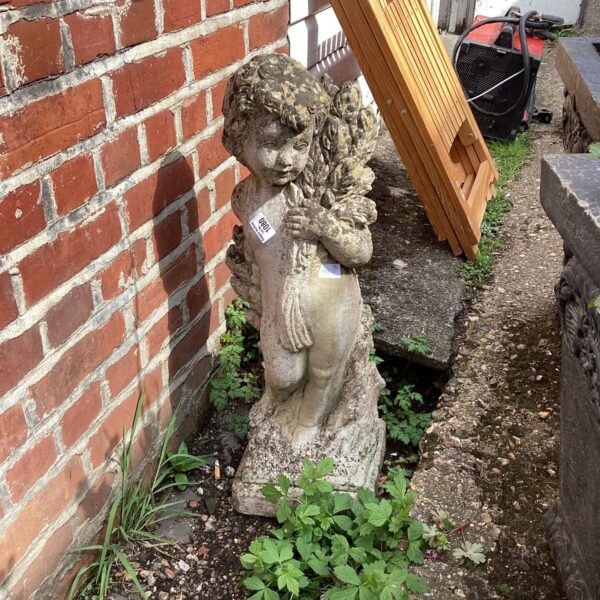 Vintage concrete cherub garden ornament in a garden setting.
