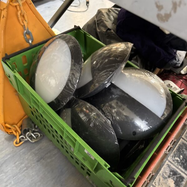 Bulk lot of new circular wall lights in a storage container.