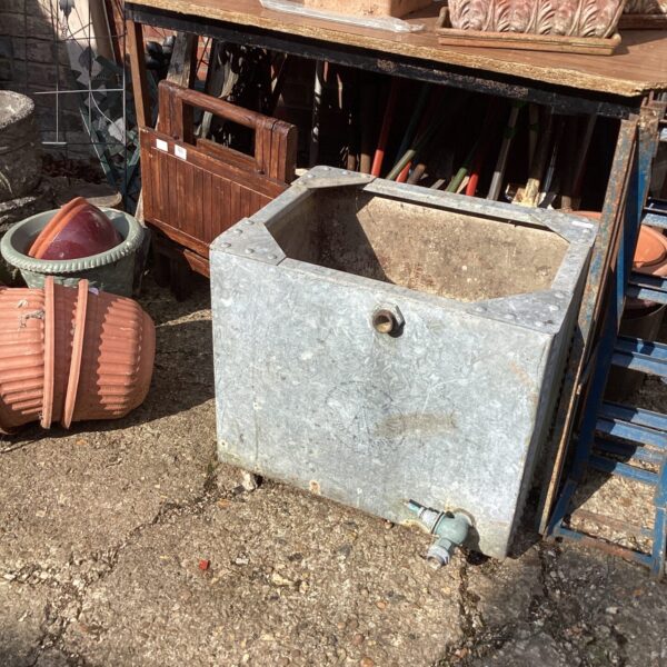 Vintage galvanised water tank in a garden setting.