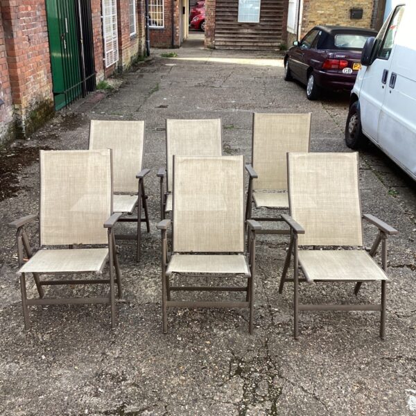 Six vintage reclining garden chairs in a garden setting.