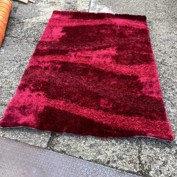 Close-up of a wine-coloured shag rug with a deep pile.