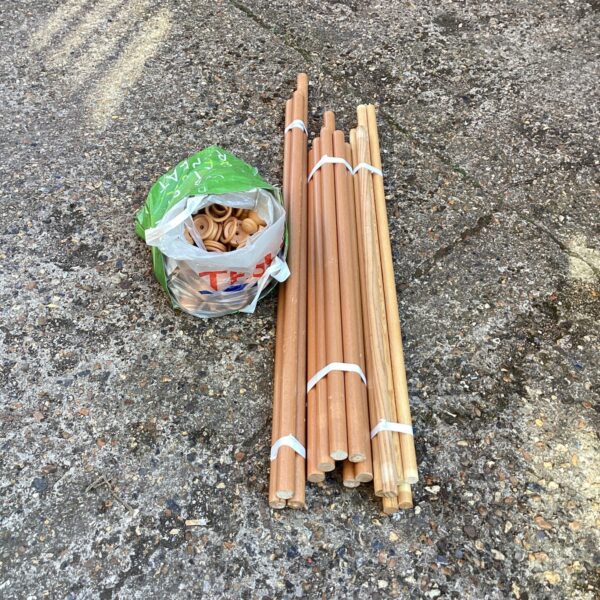 Large lot of wooden curtain poles bundled together.