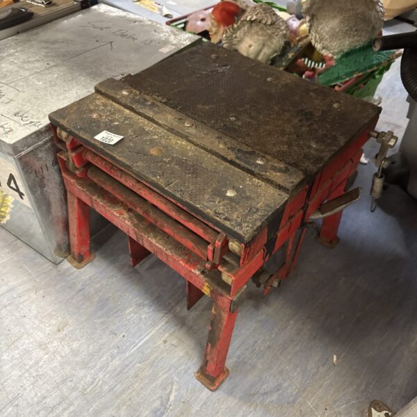 Red metal motorcycle lift stand for garage use.