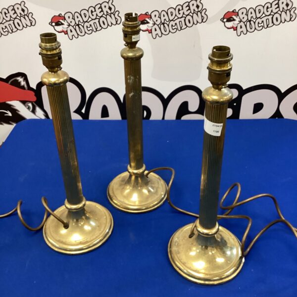 Three brass pillar table lamps on a white background.