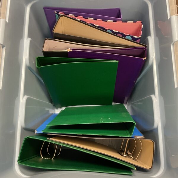 Crate of green and purple lever arch files for document storage.