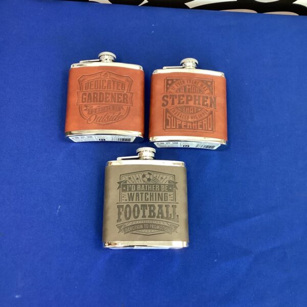Lot of three novelty hip flasks in stainless steel.