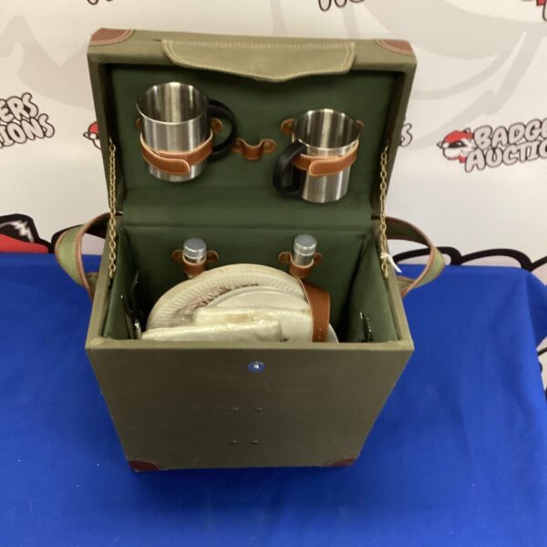 Open vintage canvas picnic set displaying cups and plates.